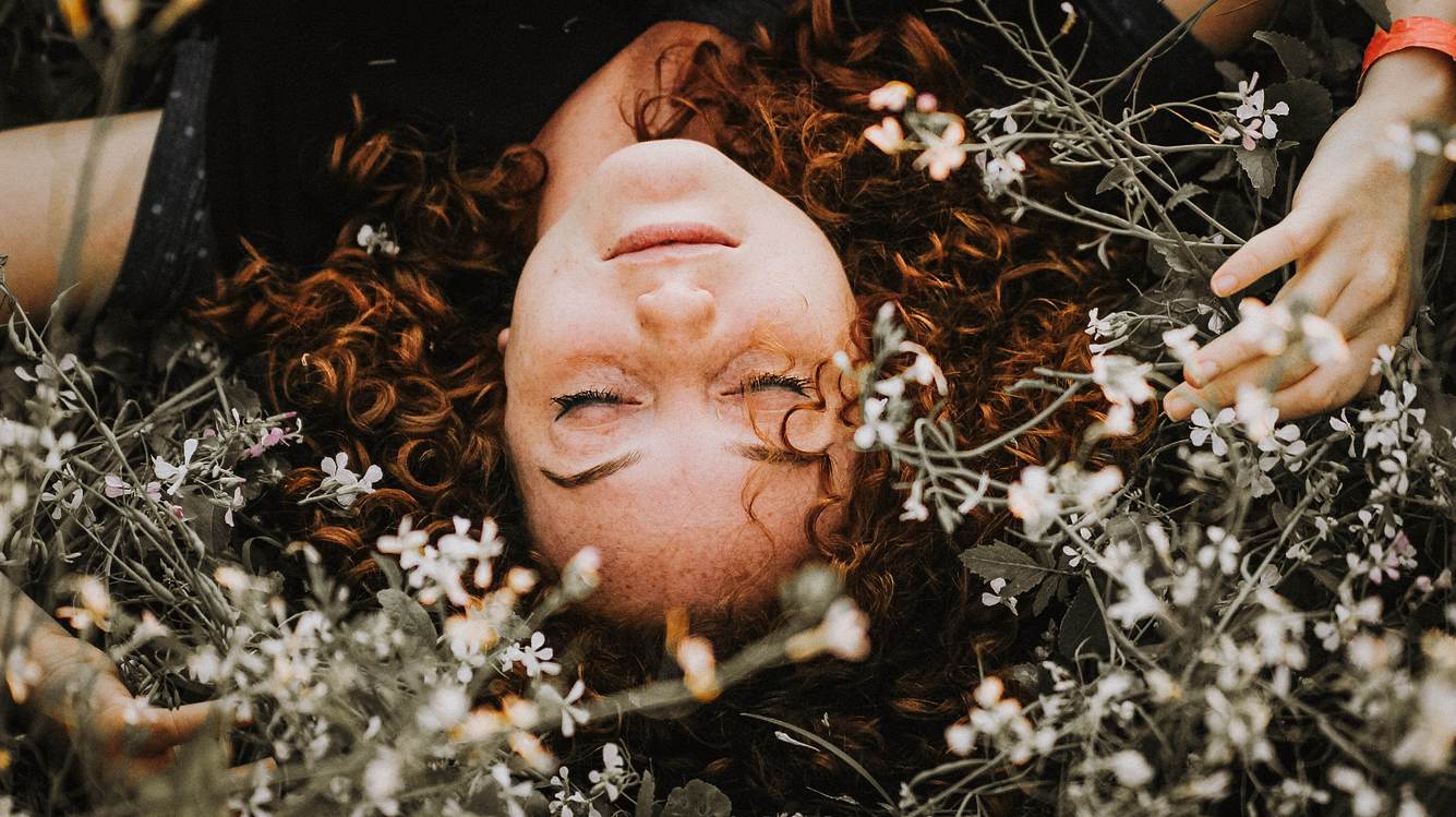 Frau liegt auf einer Blumenwiese 