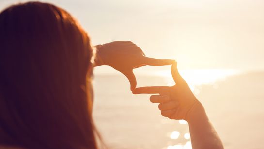 Person blickt durch Finger auf Meer - Foto: canva.com