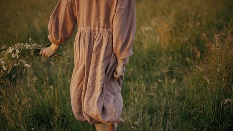 Frau wandert in Abenddämmerung durch ein Feld - Foto: canva.com