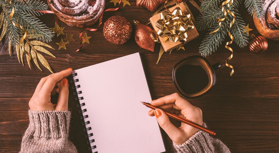 Person schteibt auf Block neben Weihnachtsdeko