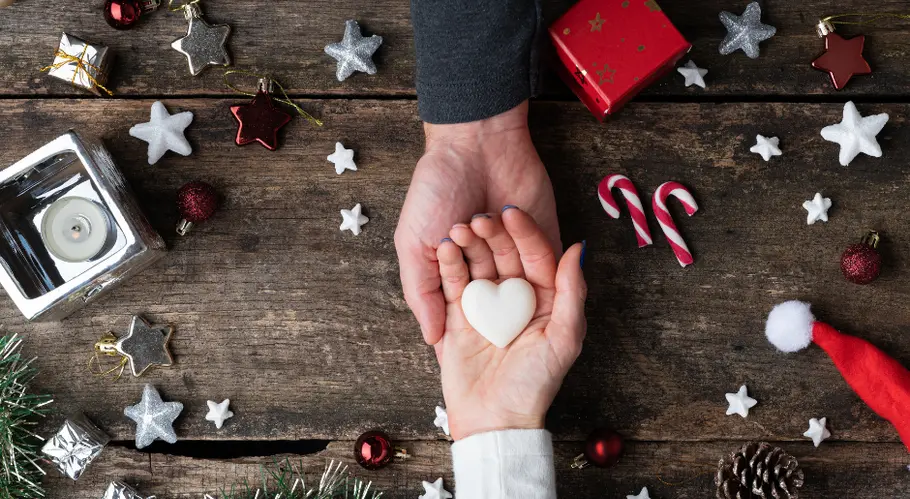 Weihnachtsgrüße 2023: Schöne Sprüche für deine Liebsten Hände halten Herz auf Tisch