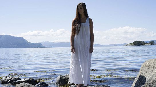 Frau im weißen Kleid steht am Wasser - Foto: plainpicture