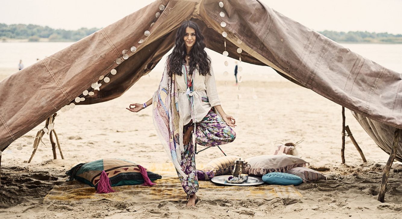 Frau in Yoga-Pose vor einem Zelt in der Wüste