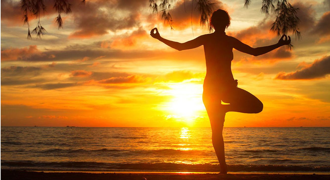 Frau in Yoga-Pose vor Sonnenuntergang