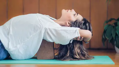 Person liegt auf Yoga-Block - Foto: canva.com